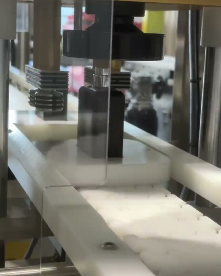 A black The Fragrance World bottle travelling down the filling line